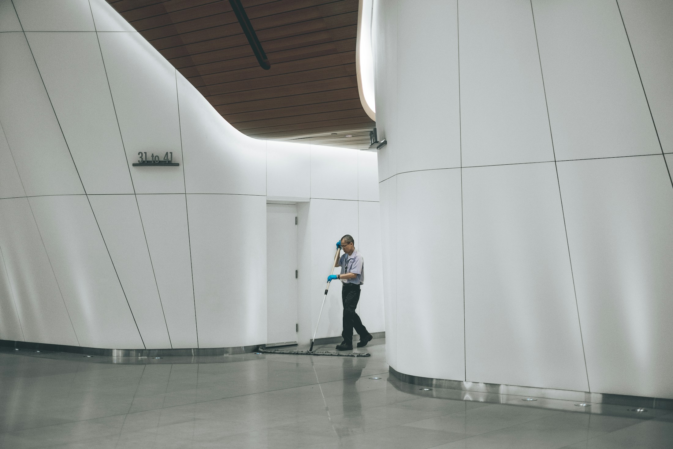 Worker cleaning a bright shared interior corridor