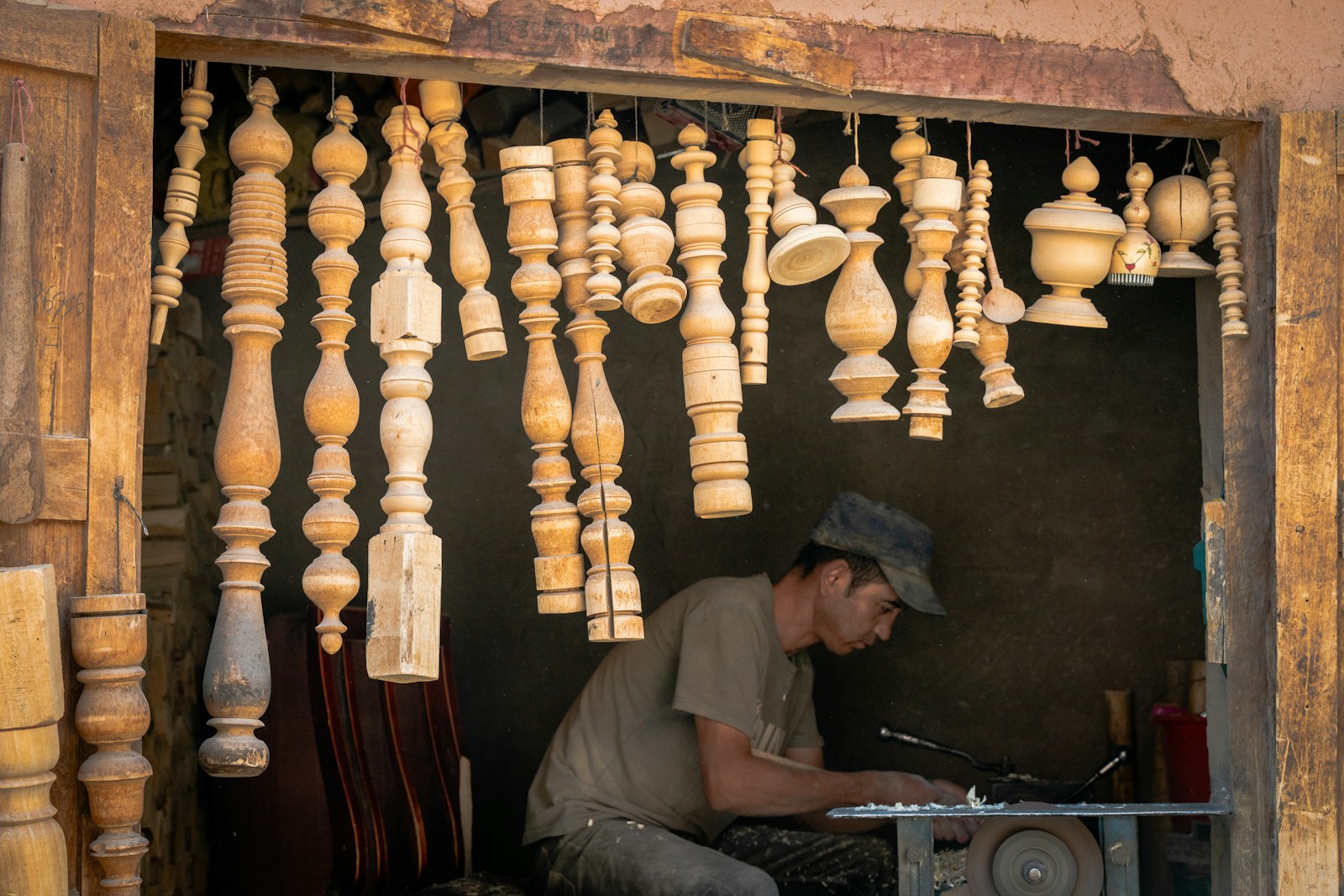 Woodturner working beneath hanging carved pieces